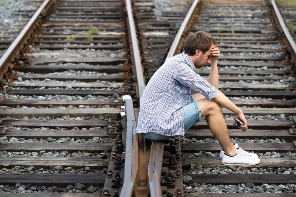 Person looking worried, sitting on a railway