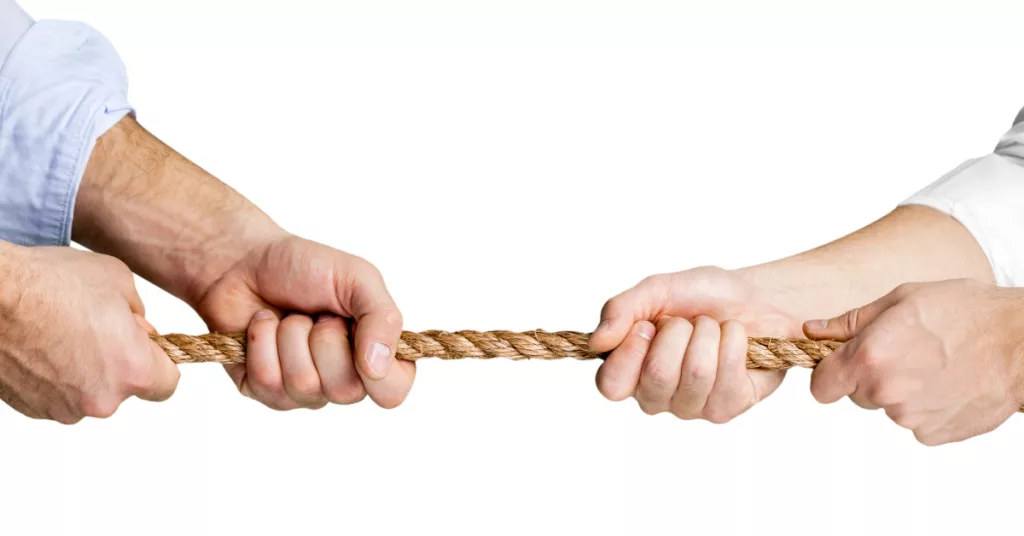 Conflict: Why We Get Into It, How to Get Out of It, and Strategies for Conflict Resolution. Image of two people playing tug of war.